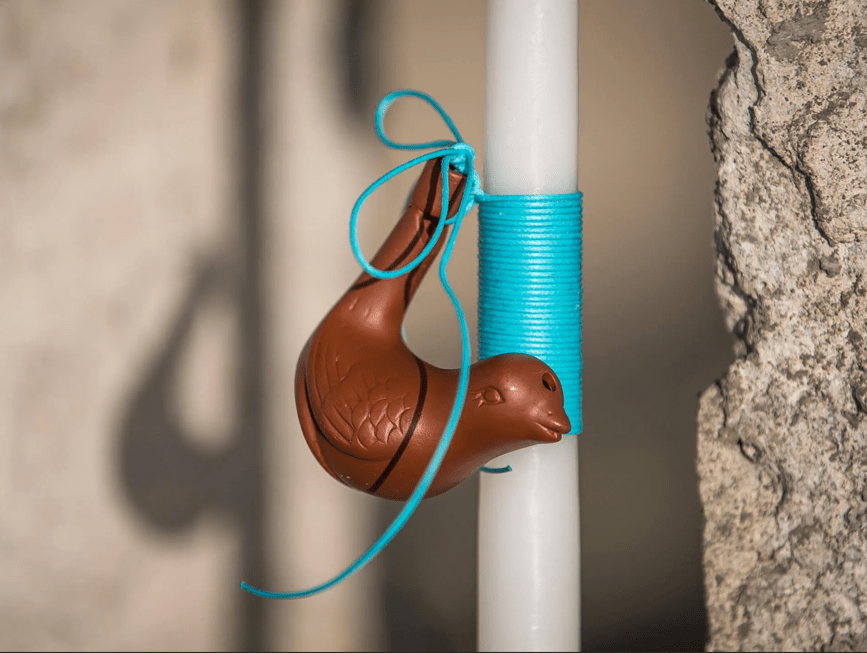 Λαμπάδα με κεραμικό παιχνίδι «Λαλίτσα» από το Cycladic Shop. Η λαλίτσα, ή νεροσφυρίχτρα, είναι ένα παραδοσιακό μουσικό παιχνίδι που έχει αγαπηθεί από γενιές παιδιών. Πρόκειται για ένα μικρό, συνήθως κεραμικό, αντικείμενο σε σχήμα πουλιού το οποίο διδάσκει στα παιδιά βασικές έννοιες ήχου και μουσικής, ενώ ταυτόχρονα τους επιτρέπει να μιμηθούν φυσικούς ήχους, όπως το κελάηδισμα των πουλιών