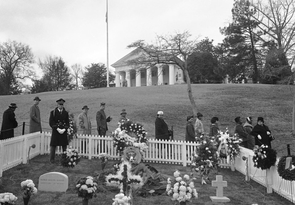 Γρανιτένιες ταφόπλακες σηματοδοτούν τους τάφους του Πάτρικ Μπουβιέ Κένεντι, αριστερά, και της Μπέιμπι Γκερλ Κένεντι, δεξιά, εκατέρωθεν του τυλιγμένου με φοίνικες τάφου του πατέρα τους, του Προέδρου Τζον Φ. Κένεντι, στο Εθνικό Νεκροταφείο του Άρλινγκτον, στις 11 Δεκεμβρίου 1963 /