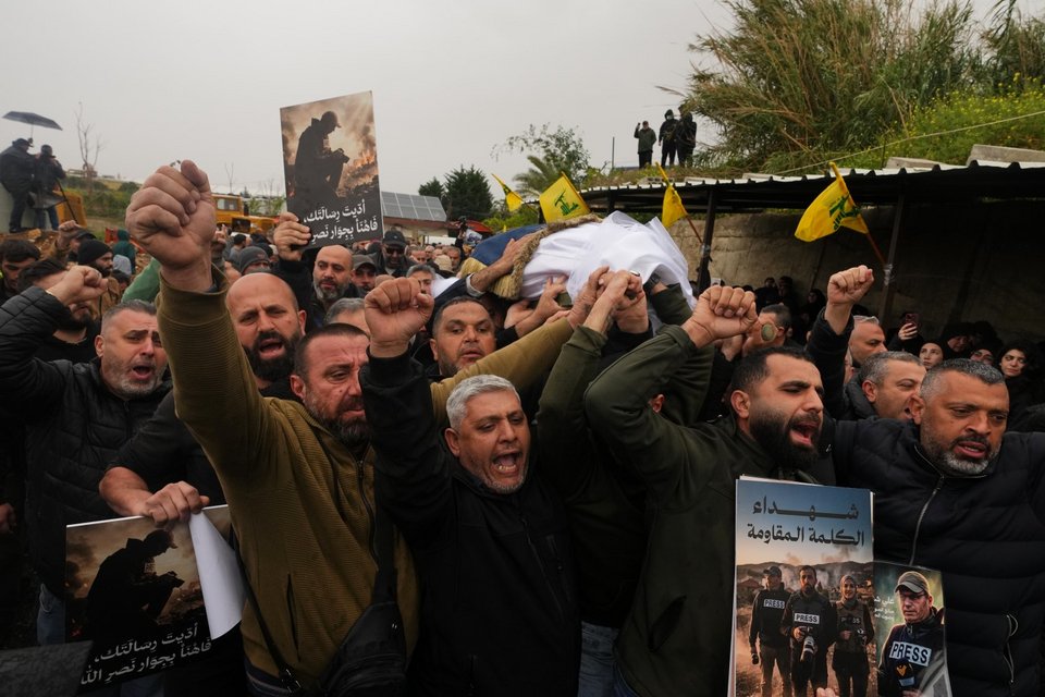 Πενθούντες συγκεντρώνονται κοντά σε έναν φρεσκοσκαμμένο τάφο κατά τη διάρκεια της κηδείας των 3 λιβανέζων δημοσιογράφων, σε προσωρινό νεκροταφείο στη Νταχίγιε, στα νότια προάστια της Βηρυτού / Φωτογραφία: AP / Hassan Ammar  