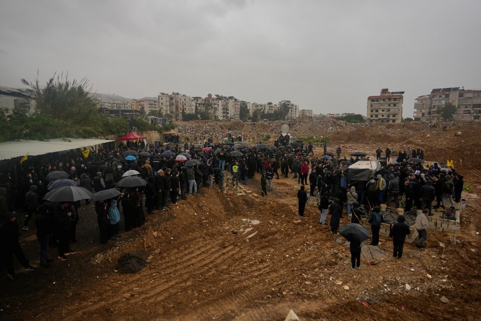 Πενθούντες συγκεντρώνονται κοντά σε έναν φρεσκοσκαμμένο τάφο κατά τη διάρκεια της κηδείας των τριών λιβανέζων δημοσιογράφων, σε προσωρινό νεκροταφείο στη Νταχίγιε, στα νότια προάστια της Βηρυτού / Φωτογραφία: AP / Hassan Ammar   