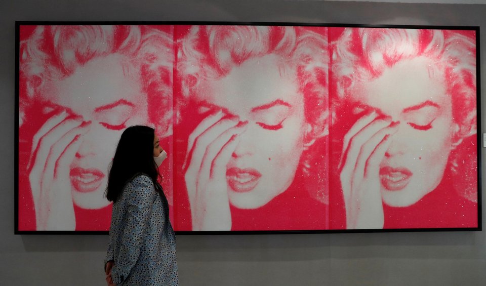 Γυναίκα κοιτάζει πόστερ που απεικονίζει τη Μ. Μονρόε να πιάνει το κεφάλι της, έτοιμη να κλάψει / Φωτογραφία: AP