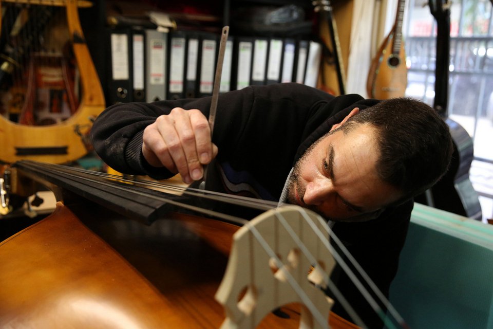 Ο Σωκράτης Μπρας τοποθετεί και ελέγχει τον «καβαλλάρη», τεντωτήρα των χορδών,σε ένα χειροποίητο κόντρα μπάσο στο εργαστήριο του πατέρα του, Νικόλα, στο οποίο, εδώ και 40 χρόνια, κατασκευάζονται χειροποίητα έγχορδα μουσικά όργανα