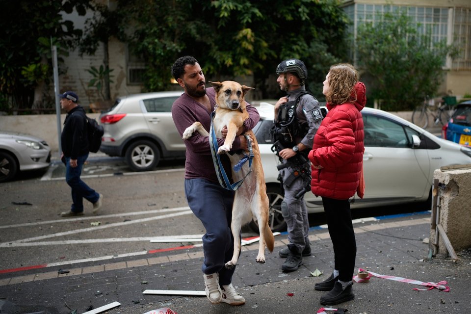 Κάτοικος του Τελ Αβίβ μεταφέρει τον σκύλο του, περνώντας μέσα από θραύσματα / AP