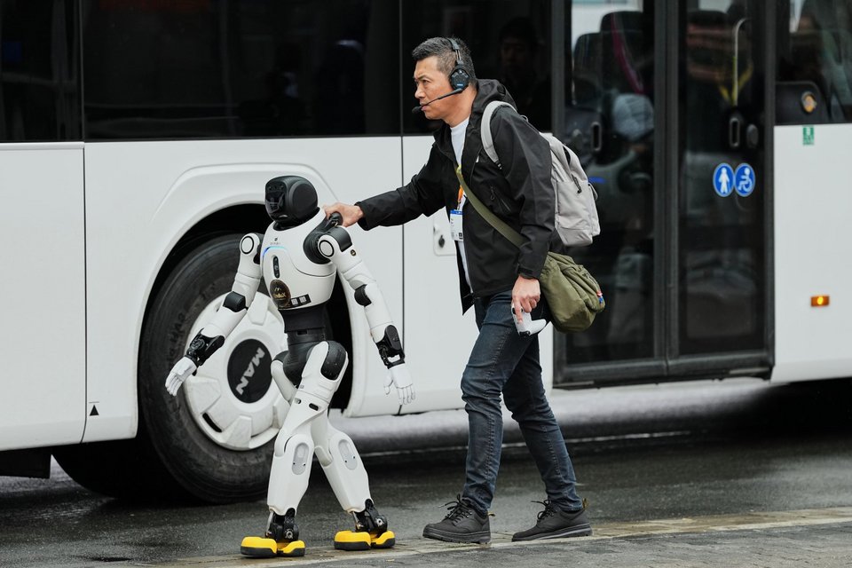 Ένα ανθρωποειδές ρομπότ περπατάει δίπλα σε έναν άνδρα στην Hanover Messe, τη μεγαλύτερη εμπορική έκθεση βιομηχανικής τεχνολογίας στον κόσμο, στο Ανόβερο της βόρειας Γερμανίας / Φωτογραφία: AP 