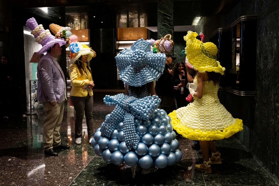 Άνθρωποι που φορούν στολές με μπαλόνια στέκονται μέσα σε ένα κτίριο στο Rockefeller Center κατά τη διάρκεια έντονων βροχοπτώσεων στην παρέλαση του Easter Bonnet στην Πέμπτη Λεωφόρο /Φωτογραφία: AP 
