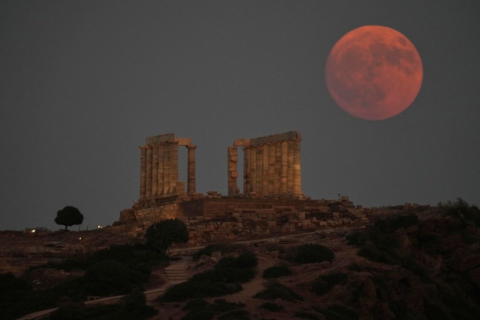 Tο «Φεγγάρι του Οξύρρυγχου» ανατέλλει κόκκινο πίσω από τον αρχαίο ναό του Ποσειδώνα στο Σούνιο, 8 Αυγούστου 2025. (AP Photo/Thanassis Stavrakis)
