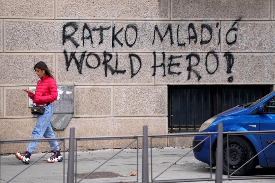 Μια γυναίκα περνάει δίπλα από ένα γκράφιτι στο Βελιγράδι της Σερβίας, που γράφει «Ράτκο Μλάντιτς, Παγκόσμιος Ήρωας», 2022 (AP Photo/Darko Vojinovic)