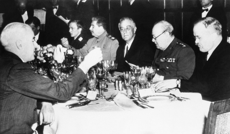 Στο βάθος, αριστερά, ο Ιωσήφ Στάλιν, με ανοιχτόχρωμη στολή, ο Αμερικανός Πρόεδρος Φράνκλιν Ντ. Ρούζβελτ, και ο Βρετανός Πρωθυπουργός Ουίνστον Τσόρτσιλ, κάθονται μαζί στο τελικό δείπνο που διοργανώθηκε στο πλαίσιο της διάσκεψης στη Γιάλτα της Ουκρανίας στις 3 Μαρτίου του 1945