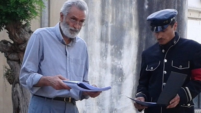 Αντρας με γαλάζιο πουκάμισο και ενας αστυνομικός