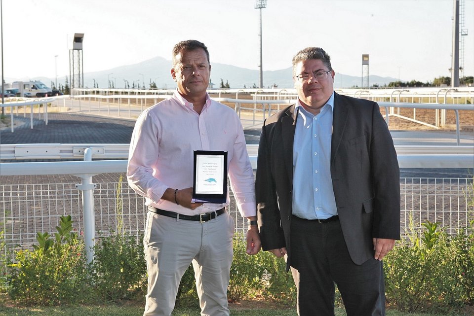 O Chief Operation Officer της ΙΠΠΟΔΡΟΜΙΕΣ Α.Ε.  Κωνσταντίνος Αλεξόπουλος  απονέμει το Τρόπαιο Βάσος Βασιλείου στον Χρήστο Θεοδωράκη, εκπρόσωπο της ιδιοκτησίας  του ίππου ΕΛΕΓΚΑΝΤΛΥ ΜΠΑΟΥΝΤ.