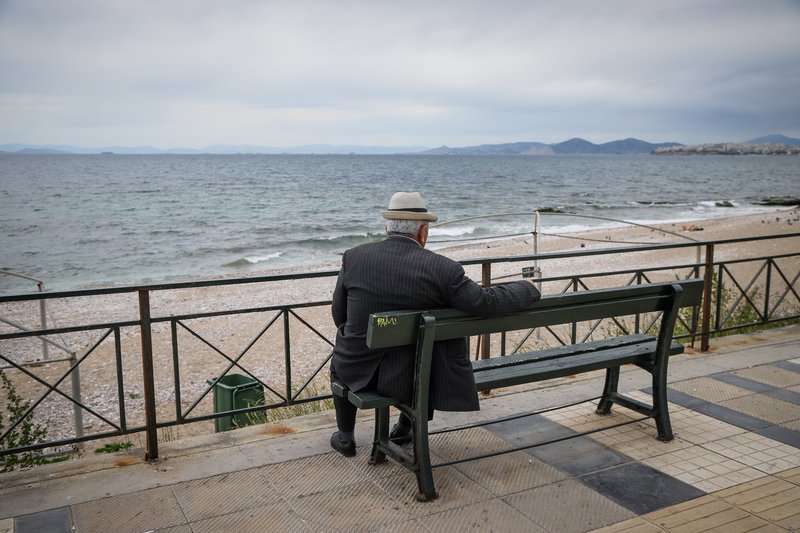 Κύριος σε παγκάκι βλέπει τη θάλασσα, στην παραλία του Παλαιού Φαλήρου
