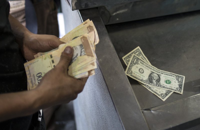 Άνδρας μετρά χαρτονομίσματα σε ATM στη Βενεζουέλα.