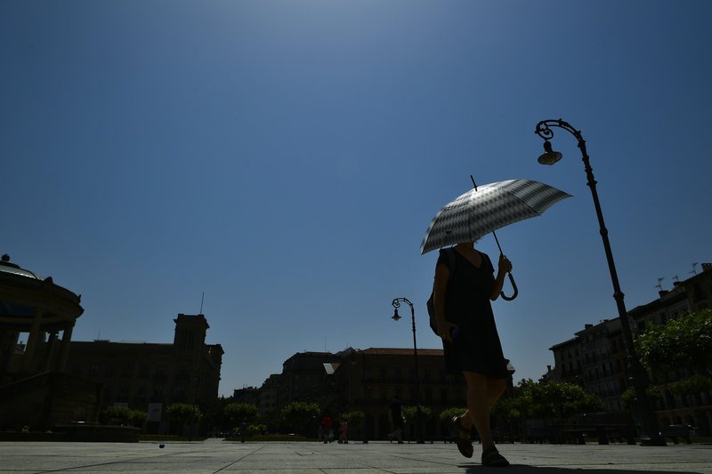 Ομπρέλα για να προστατευτεί απ' τον ήλιο επιστράτευσε αυτή η Ισπανίδα στην Παμπλόνα.