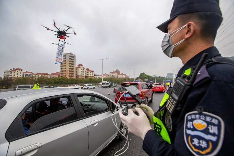 Αστυνομικός χειρίζεται drone με πινακίδα που φέρει κωδικό QR σε σταθμό διοδίων στη Σενζέν της νότιας Κίνας.