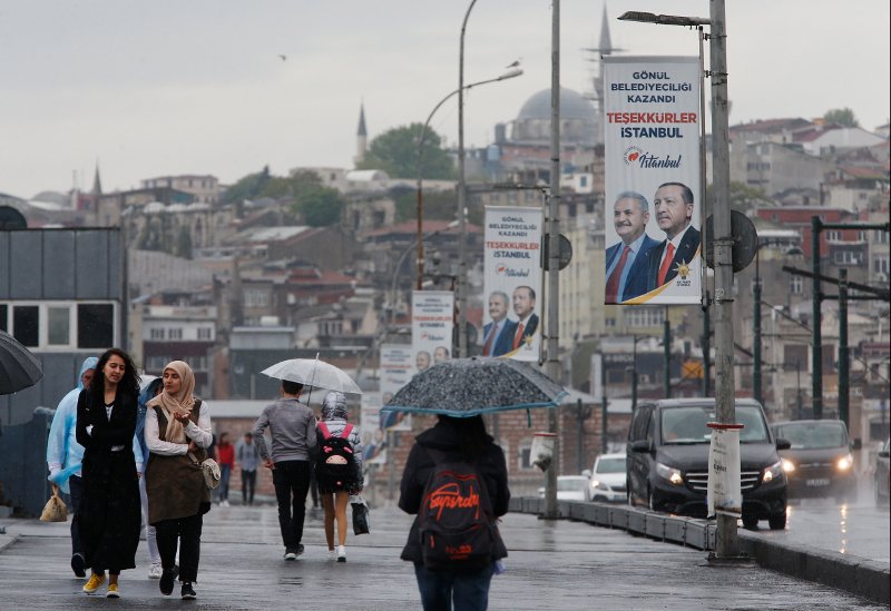 Κάτοικοι της Κωνσταντινούπολης περνούν μπροστά από αφίσες του υποψηφίου του Ερντογάν, Μπιναλί Γιλντιρίμ.