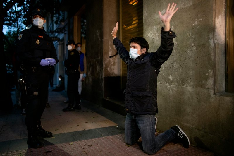 Διαδηλωτής με μάσκα μπροστά σε αστυνομικό στη διάρκεια διαδήλωσης στη Μαδρίτη