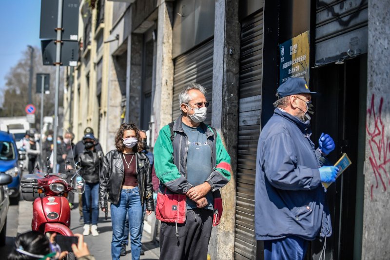Ιταλοί περιμένουν στην ουρά σε τοποθεσία του Μιλανου για να παραλάβουν μάσκες, που έστειλε η Κίνα στο πλαίσιο ανθρωπιστικής βοήθειας.