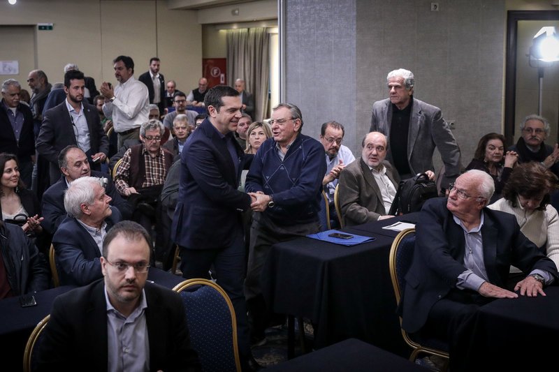 Ο Αλέξης Τσίπρας χαιρετάει τον κόσμο κατά την άφιξή του. Ο Θανάσης Θεοχαρόπουλος τον περιμένει να καθίσει δίπλα του.