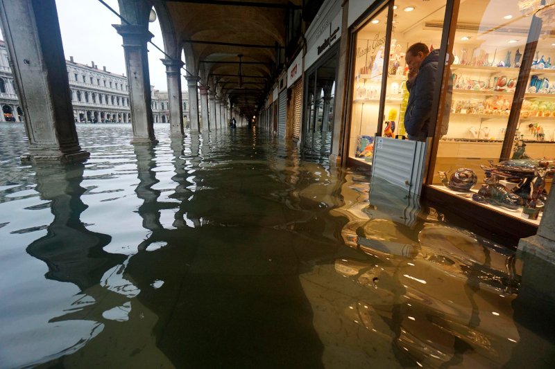 Καταστηματάρχης στη Βενετία κοιτά με απόγνωση τα νερά που πολιορκούν την επιχείρησή του / Φωτογραφία: ΑΡ