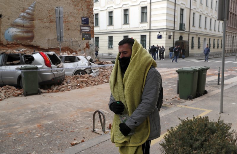 Ένας άνδρας περπατά μπροστά από ένα γκρεμισμένο κτίριο