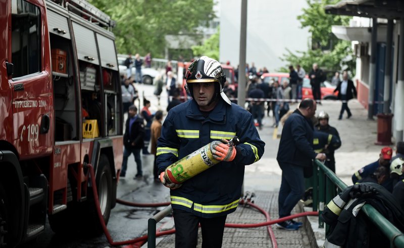 Ενας πυροσβέστης που συμμετείχε στην κατάσβεση της πυρκαγιάς στο ΑΠΘ περπατά κρατώντας στα χέρια του μια φιάλη με οξυγόνο