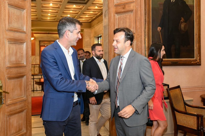 Ο Κώστας Μπακογιάνης χαιρετά τον Γιώργο Μπρούλια στην παράδοση-παραλαβή στο δημαρχείο Αθήνας στην πλατεία Κοτζιά