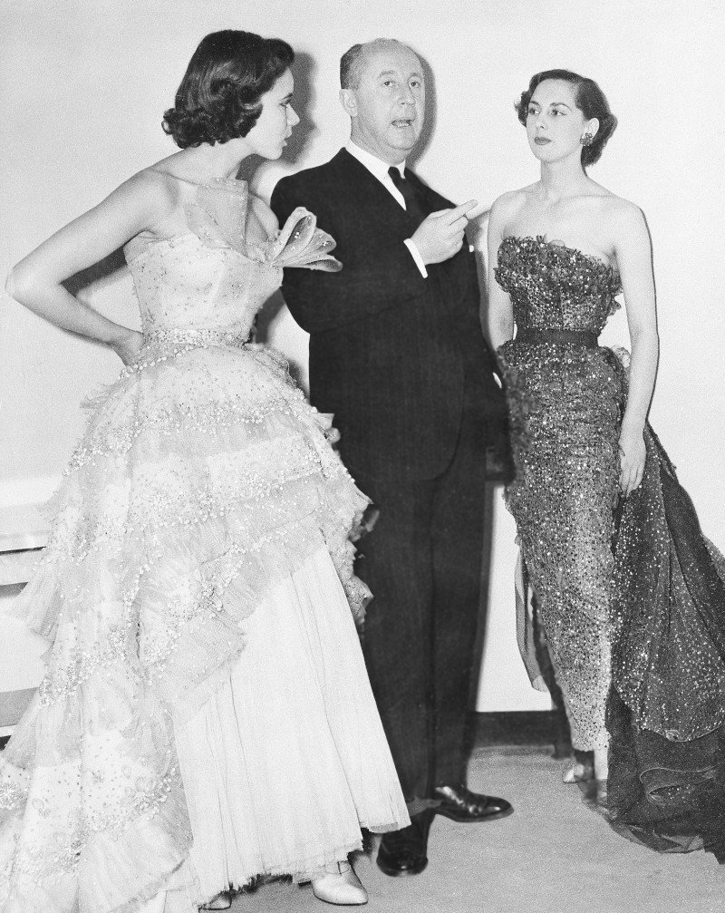 Ο Γάλλος σχεδιαστής μόδας Christian Dior με δύο μοντέλα στο Savoy Hotel του Λονδίνου, στις 28 Απριλίου 1950/Φωτογραφία Associated Press