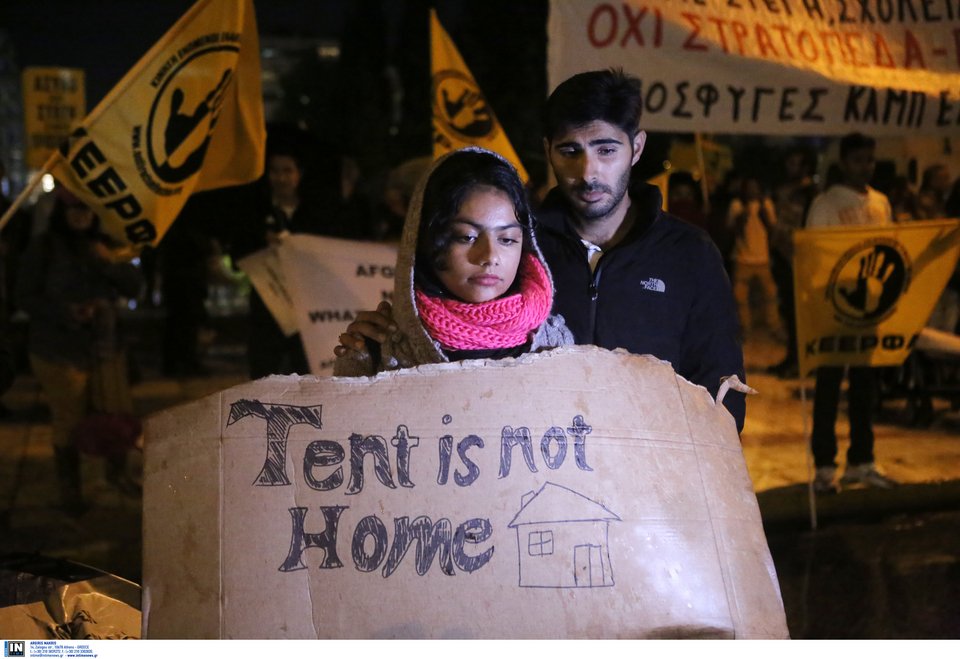 Διαδηλώτρια κρατά χαρτόνι στο οποίο γράφει «Η σκηνή δεν είναι σπίτι»