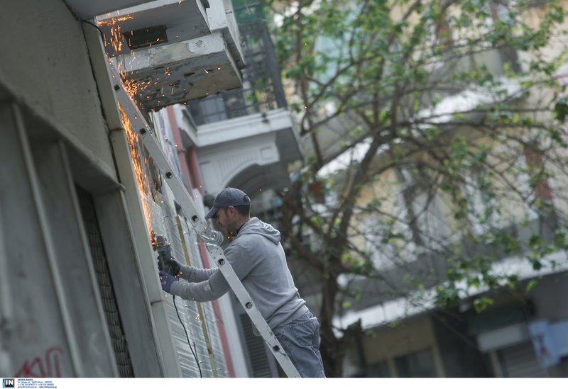 Εργάτης σφραγίζει τα κτίρια μετά την απομάκρυνση των καταληψιών