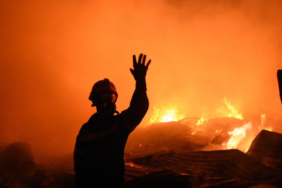 Πυροσβέστης κάνει νόημα ενώ πίσω του υπάρχει φωτιά