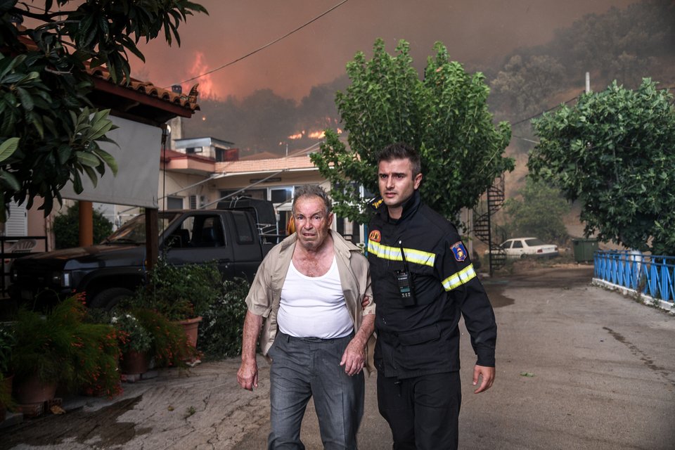 Πυροσβέστης συνοδεύει κάτοικο του χωριού Κοντοδεσπότι κατά τη διάρκεια της εκκένωσης