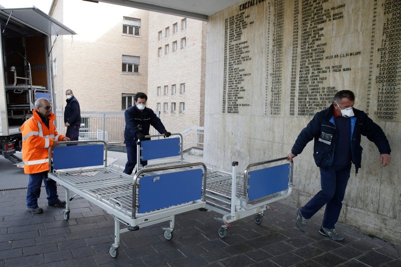 Μέλη ιατρικού προσωπικού μεταφέρουν κρεβάτια σε νοσοκομείο στο Κοντόνιο προκειμένου να αντιμετωπίσουν τις αυξημένες ανάγκες εξαιτίας του κορωνοϊού