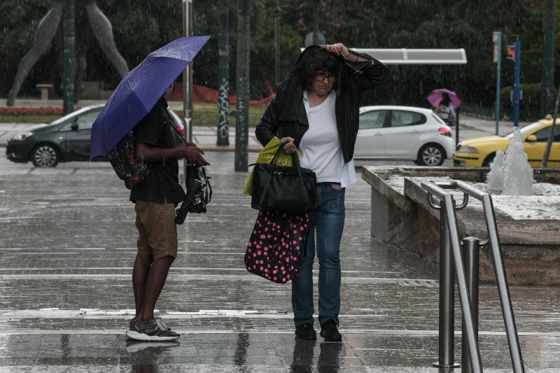 Γυναίκα προσπαθεί να προφυλαχθεί από την έντονη βροχόπτωση στην Αθήνα/ Φωτογραφία: Eurokinissi