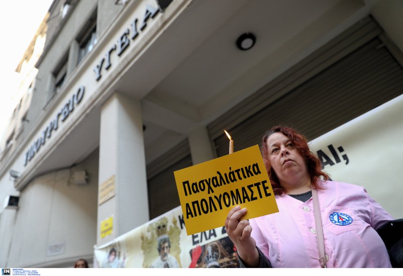 Μια καθαρίστρια με ένα κερί στο χέρι και χαρτί που γράφει «Πασχαλιάτικα απολυόμαστε»