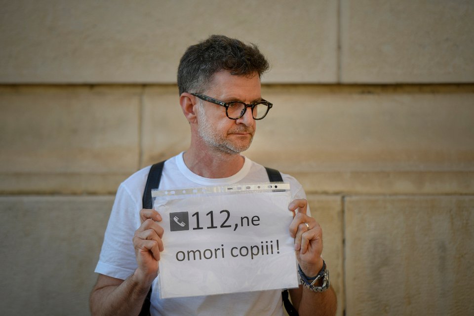 Άνδρας διαμαρτύρεται έξω από το υπουργείο Εσωτερικών της Ρουμανίας με ένα χαρτί που γράφει «112, σκοτώνεις τα παιδιά μας»