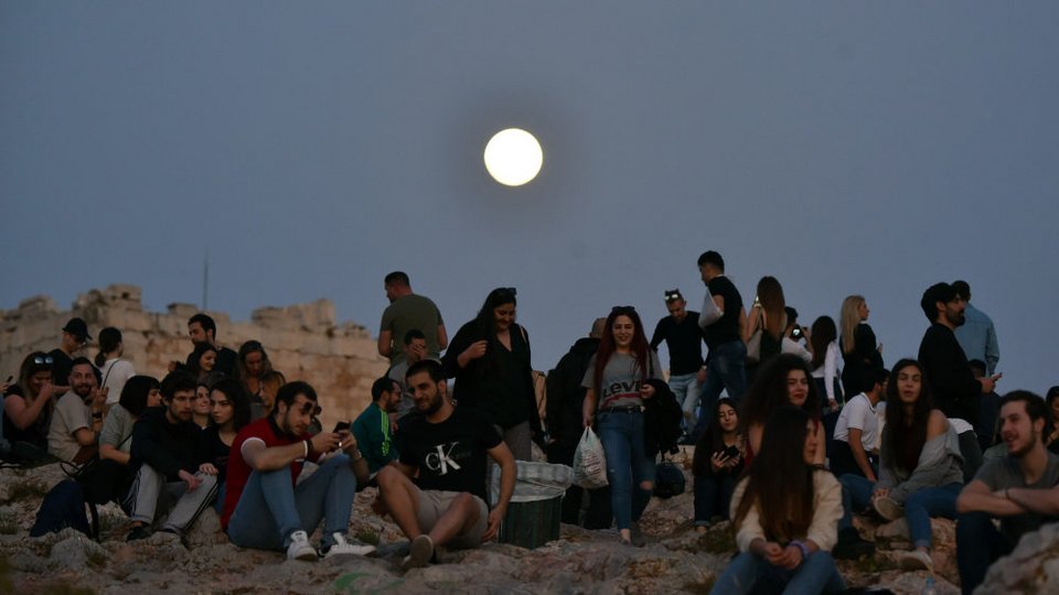 Δεκάδες κόσμου στον βράχο της Ακρόπολης το βράδυ της Τετάρτης με φόντο το σχεδόν ολόγιωμο φεγγάρι