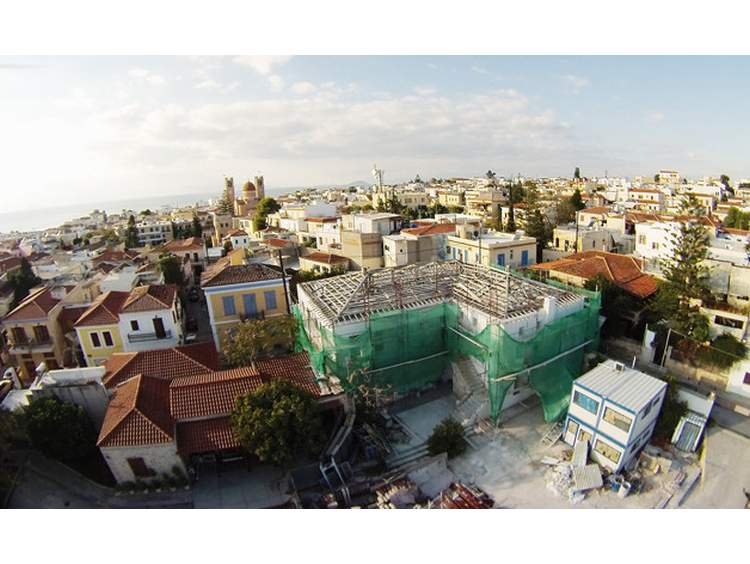 Εδώ, στη φωτογραφία από το Saronic Magazine φαίνονται οι εργασίες στο Κυβερνείο και το παράπλευρο πετρόκτιστο κτίριο της Δημοτικής Βιβλιοθήκης. Ένα κόσμημα στο κέντρο της πόλης της Αίγινας