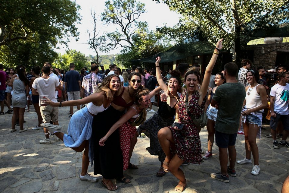 Παρέες με τουρίστες και επισκέπτες στην Λαγκάδα διασκεδάζουν πίνοντας κόκκινο κρασί από τους αμπελώνες του νησιού / Φωτογραφία: Sooc