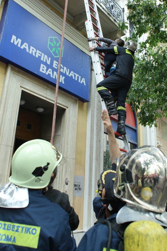 Πυροσβέστες ανεβαίνουν με σκάλα στο φλεγόμενο κτίριο της Marfin