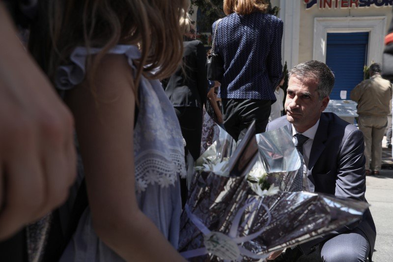 Ο Κώστας Μπακογιάννης, γονατιστός μιλά με συγγενείς θυμάτων στην τελετή μνήμης της Marfin