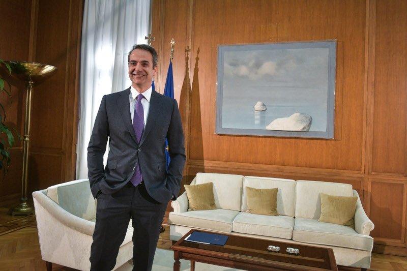 Ο Κυριάκος Μητσοτάκης χαμογελαστός ενώ περιμένει τον Αλέξη Τσίπρα