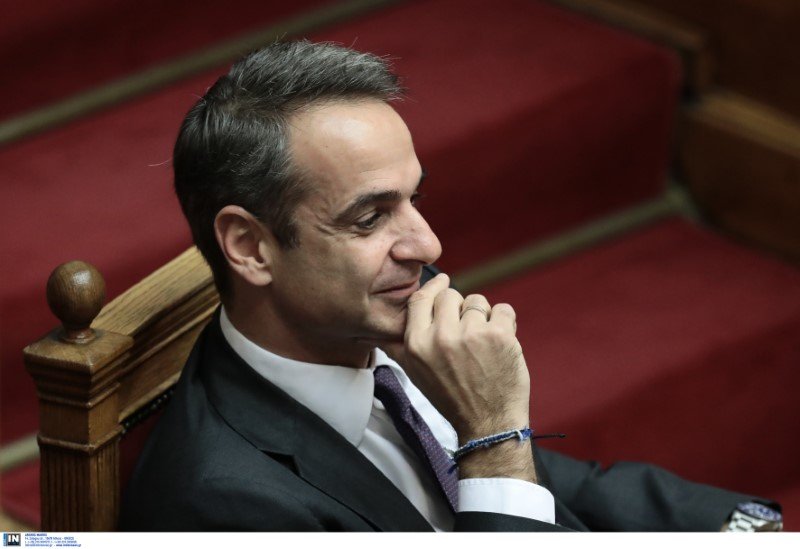 Ο πρωθυπουργός Κυριάκος Μητσοτάκης χαμογελαστός παρακολουθεί τη συζήτηση στη Βουλή
