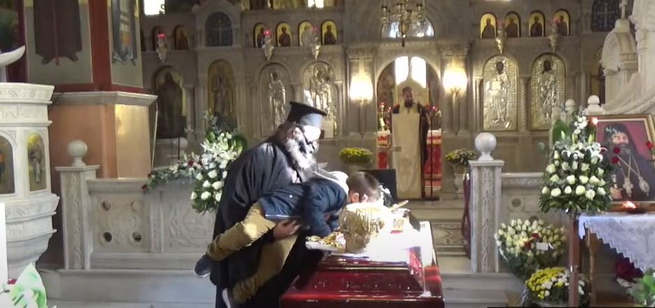 Ιερέας σηκώνει μικρό παιδί για να ασπαστεί τα άμφια του εκλιπόντος Μητροπολίτη Λαγκαδά