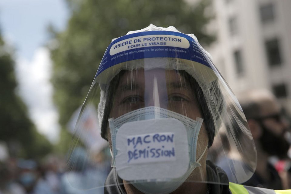 Διαδηλωτής με προστατευτικό και μάσκα που γράφει «Μακρόν παραιτήσου»