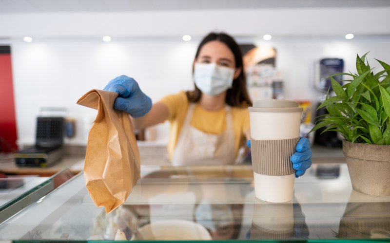 πωλήτρια δίνει χάρτινη σακούλα και χάρτινο ποτήρι