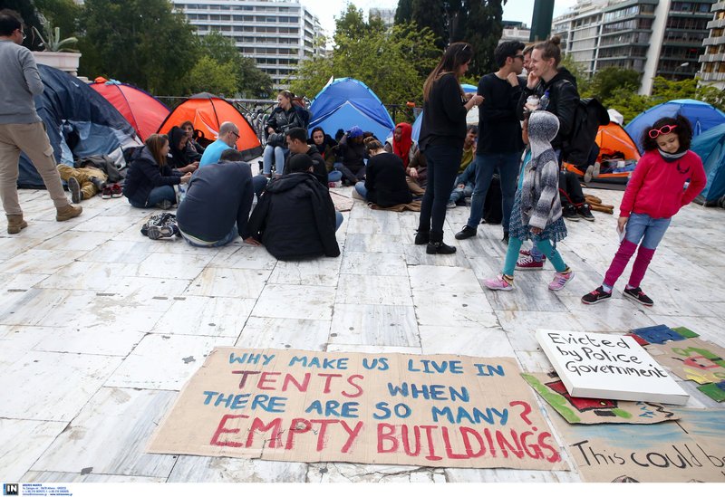 «Γιατί μας έχουν να μένουμε σε σκηνές όταν υπάρχουν τόσα άδεια κτίρια;» λέει το πρόχειρο πλακάτ -Φωτογραφία: Intimenews/ΣΤΕΦΑΝΟΥ ΣΤΕΛΙΟΣ
