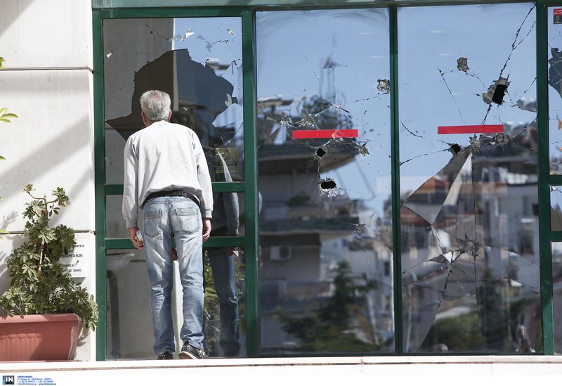 Ενας περαστικός κοιτάζει τις ζημιές που προκάλεσε ο Ρουβίκωνας στο δημαρχείο Ηλιούπολης