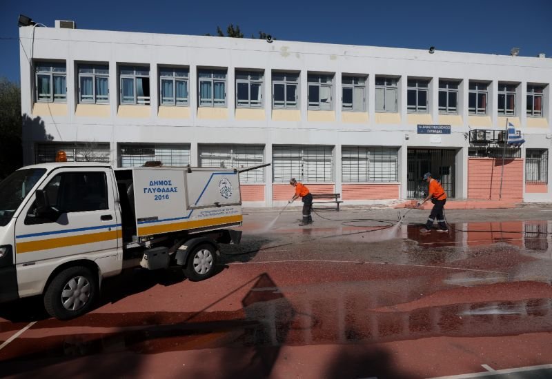 Εργαζόμενοι στη καθαριότητα του Δήμου Γλυφάδας με πλυστικά καθαρίζουν το προαύλιο του σχολείου