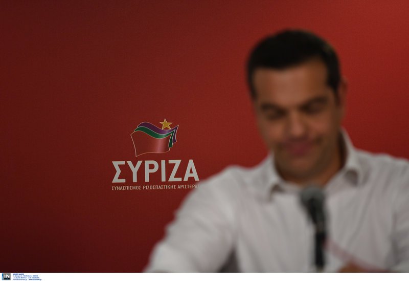 Ο Αλέξης Τσίπρας με φόντο το σήμα του ΣΥΡΙΖΑ