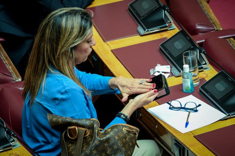 Μια βουλευτής καθαρίζει σχολαστικά το κινητό της στα έδρανα της Βουλής